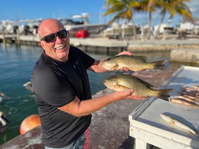 Happy Senior Man Holding Fish at Marinas